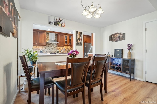 dining area with a chandelier, light wood-style floors, and baseboards