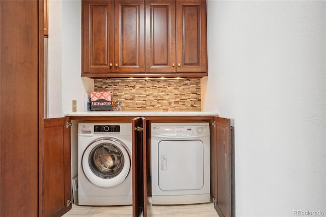 laundry room featuring washing machine and clothes dryer, cabinet space, and a dry bar