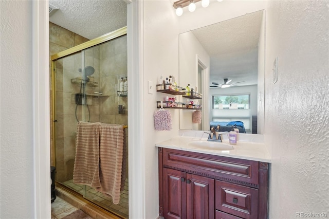 ensuite bathroom with a textured ceiling, a stall shower, vanity, and a ceiling fan