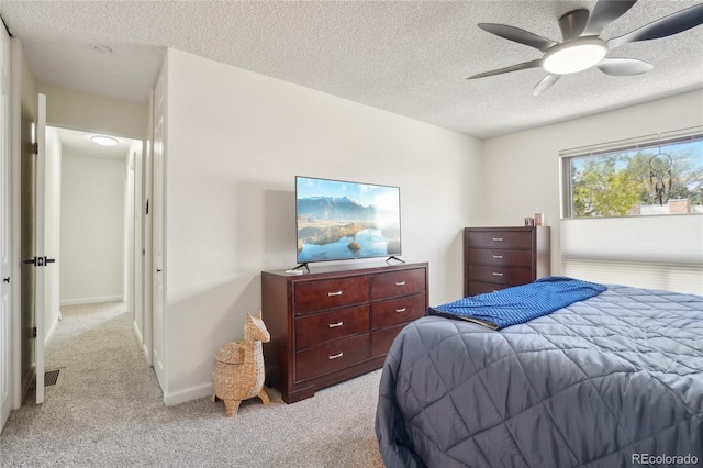 bedroom with a textured ceiling, light colored carpet, a ceiling fan, and baseboards