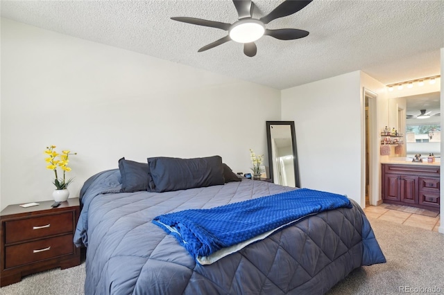 bedroom featuring light carpet, a sink, a textured ceiling, connected bathroom, and ceiling fan