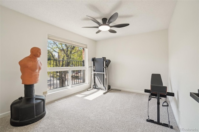 exercise room with carpet flooring, a ceiling fan, baseboards, and a textured ceiling