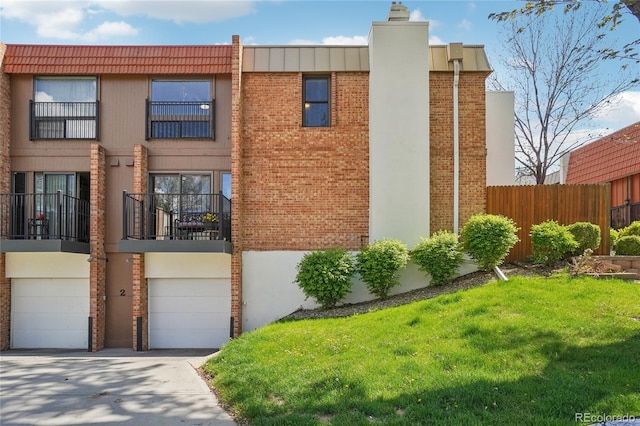 townhome / multi-family property with brick siding, a garage, driveway, and a chimney