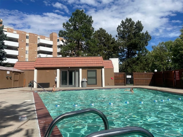 community pool with fence and an outdoor structure