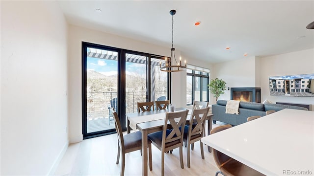 dining area featuring a chandelier, baseboards, and light wood finished floors