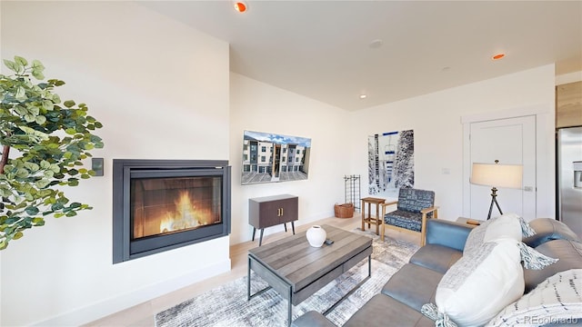 living room featuring baseboards, a glass covered fireplace, and recessed lighting