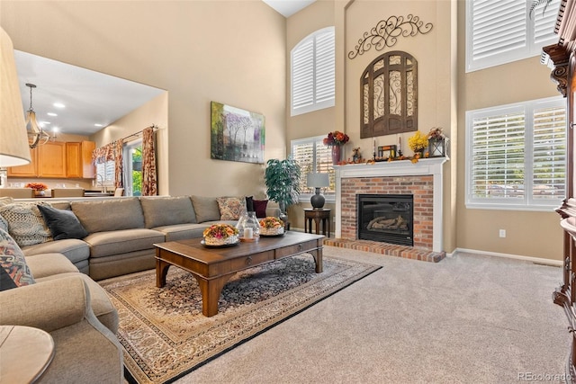 carpeted living room featuring a fireplace, a high ceiling, and a chandelier