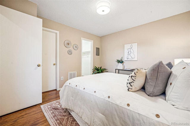 bedroom with a textured ceiling, wood finished floors, and visible vents