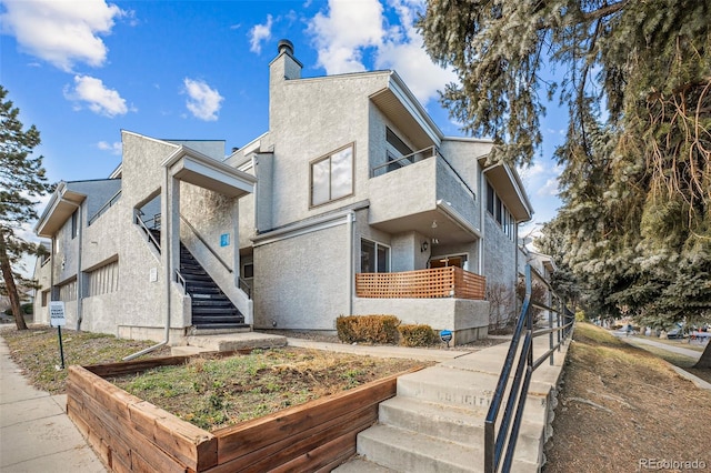 view of side of property featuring a balcony, stairs, and stucco siding