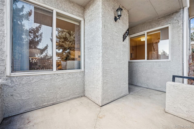 view of exterior entry with a patio area and stucco siding