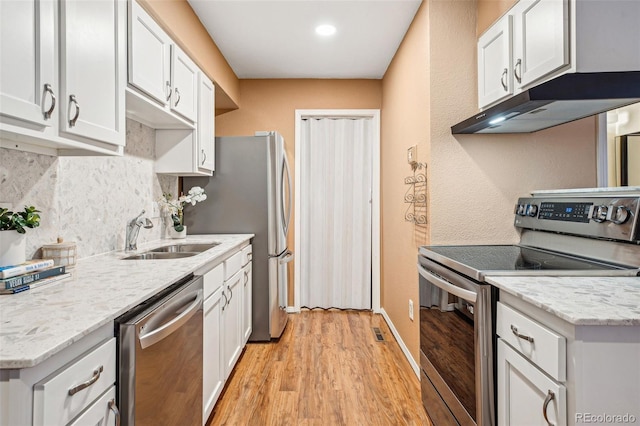 kitchen featuring stainless steel appliances, backsplash, white cabinetry, a sink, and under cabinet range hood