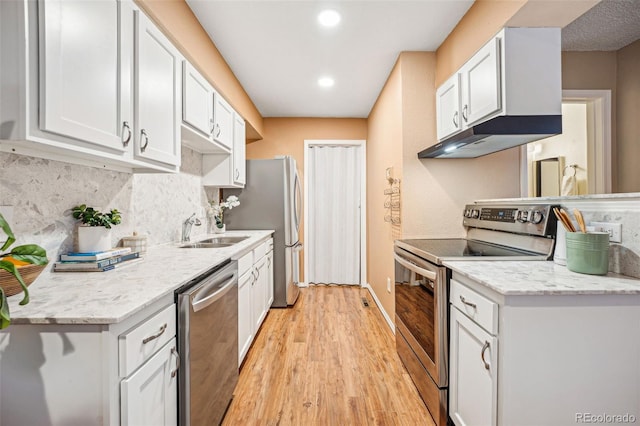 kitchen featuring appliances with stainless steel finishes, white cabinetry, a sink, and under cabinet range hood