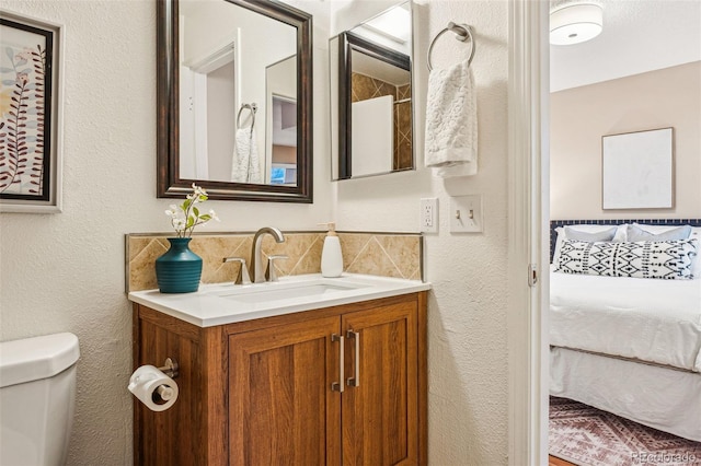 ensuite bathroom with tasteful backsplash, a textured wall, toilet, ensuite bathroom, and vanity