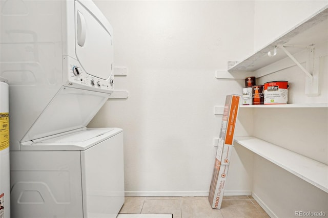 clothes washing area with baseboards, laundry area, light tile patterned flooring, and stacked washer / drying machine