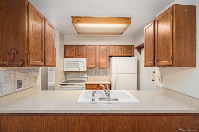 kitchen featuring sink, white appliances, decorative backsplash, and kitchen peninsula