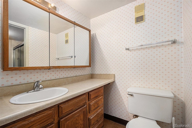 bathroom featuring a shower with door, vanity, and toilet