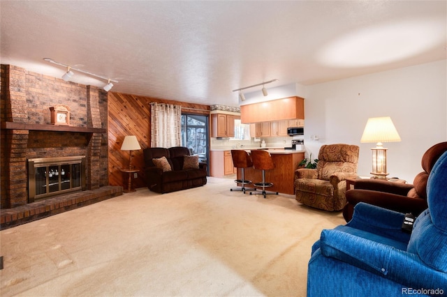 carpeted living room with wooden walls, a fireplace, a textured ceiling, and rail lighting