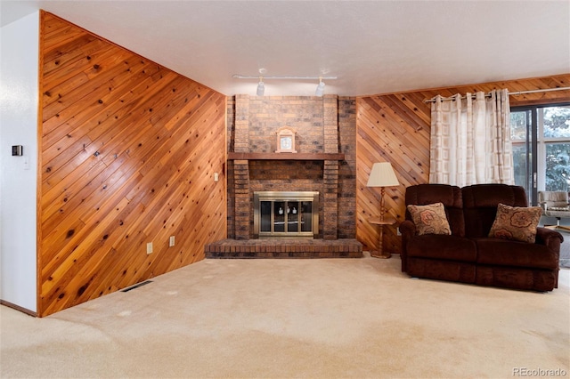 living room with a brick fireplace, carpet floors, and wooden walls