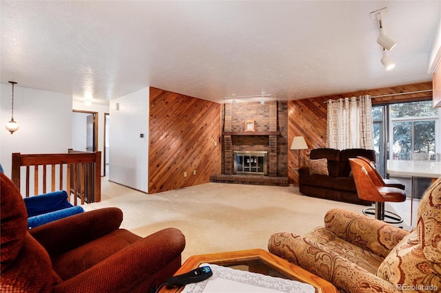 living room featuring carpet flooring, wooden walls, a brick fireplace, and rail lighting