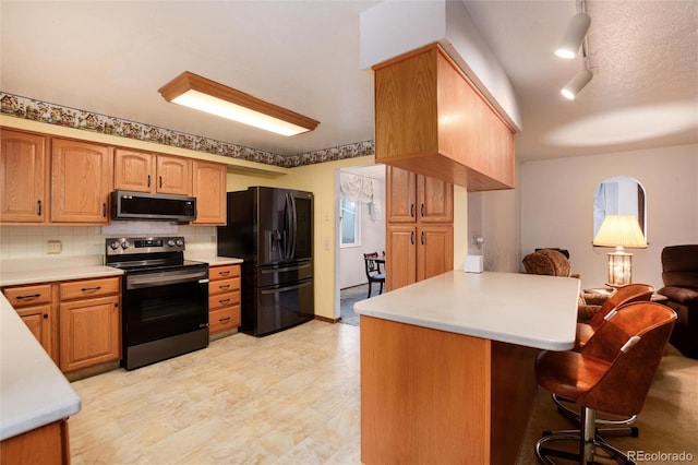 kitchen featuring stainless steel appliances, kitchen peninsula, a kitchen bar, and decorative backsplash