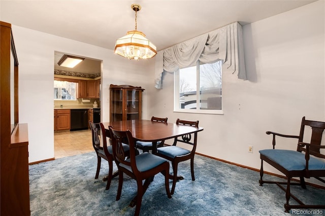 carpeted dining space featuring a notable chandelier