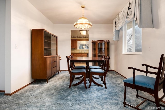 carpeted dining room featuring a chandelier