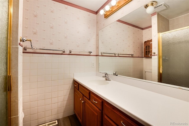 bathroom featuring walk in shower, vanity, and tile walls