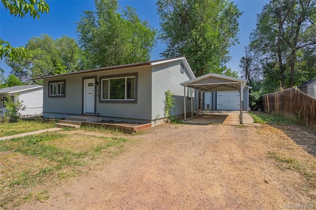 view of front of property with a carport, an outdoor structure, dirt driveway, and fence