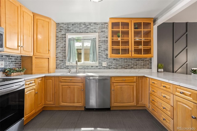 kitchen featuring light countertops, glass insert cabinets, appliances with stainless steel finishes, and a sink