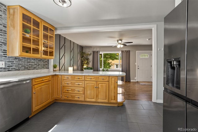kitchen with a ceiling fan, tasteful backsplash, appliances with stainless steel finishes, a peninsula, and glass insert cabinets