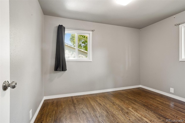 unfurnished room with baseboards and dark wood-style flooring
