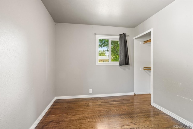 spare room featuring baseboards and wood finished floors