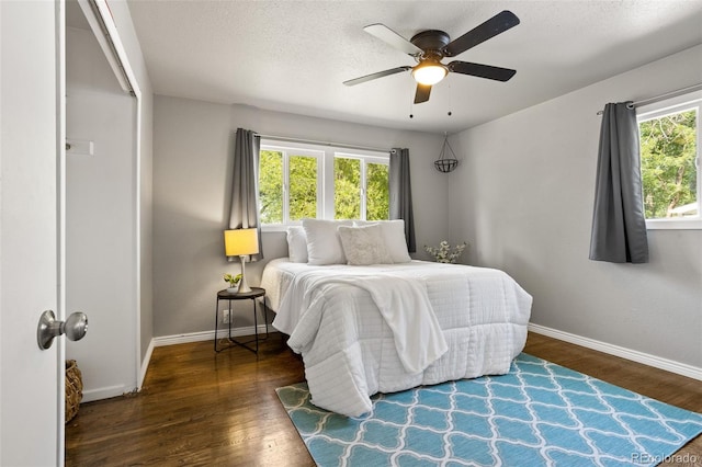 bedroom with baseboards, multiple windows, and wood finished floors