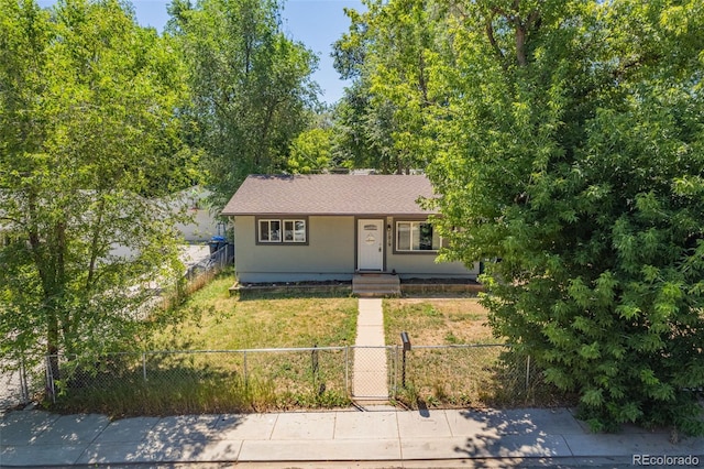 ranch-style home featuring a fenced front yard, a shingled roof, and a front lawn