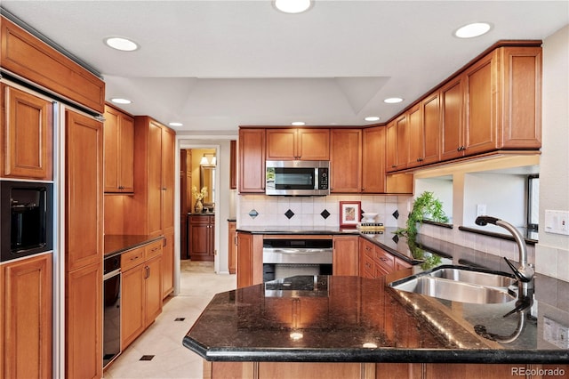 kitchen with light tile patterned floors, sink, stainless steel appliances, dark stone counters, and decorative backsplash