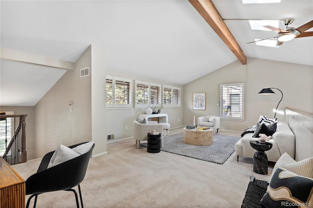 carpeted living room featuring vaulted ceiling with skylight and ceiling fan