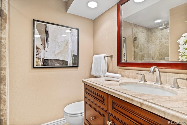 bathroom with tiled shower, vanity, and toilet