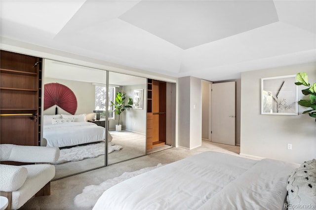 bedroom featuring light carpet, a tray ceiling, and a closet