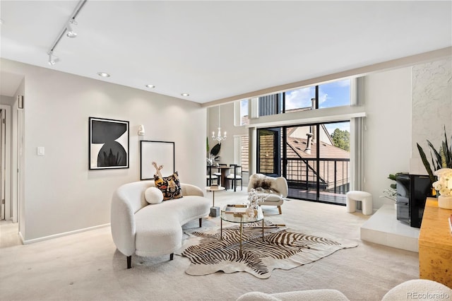 living room with light carpet, an inviting chandelier, and rail lighting