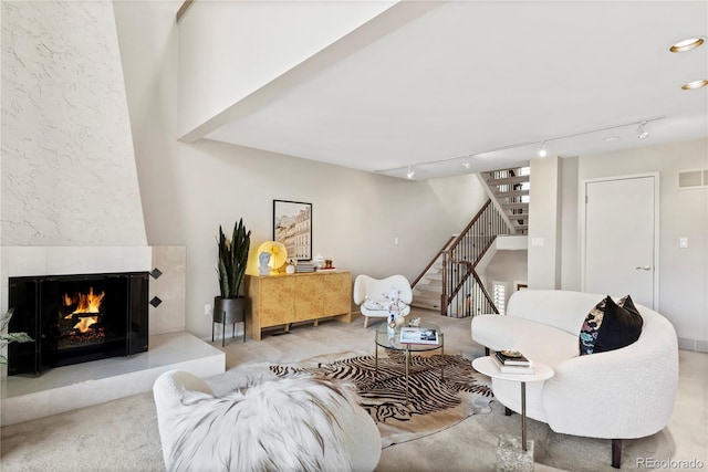 carpeted living room with a fireplace and rail lighting