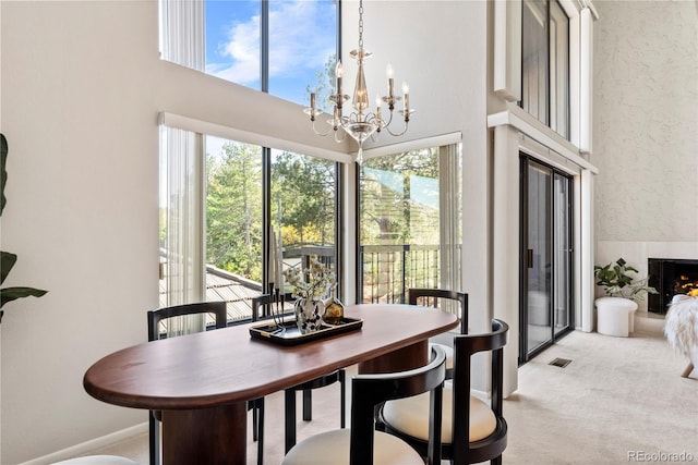 dining room featuring light carpet, plenty of natural light, a chandelier, and a high ceiling