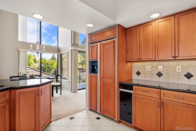 kitchen with paneled refrigerator, a chandelier, a textured ceiling, tasteful backsplash, and light carpet