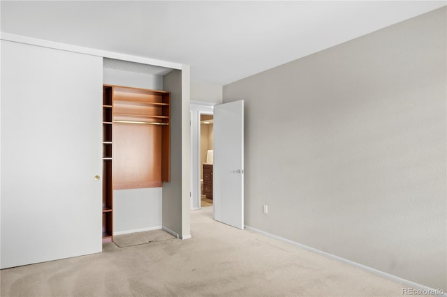 unfurnished bedroom featuring light carpet and a closet