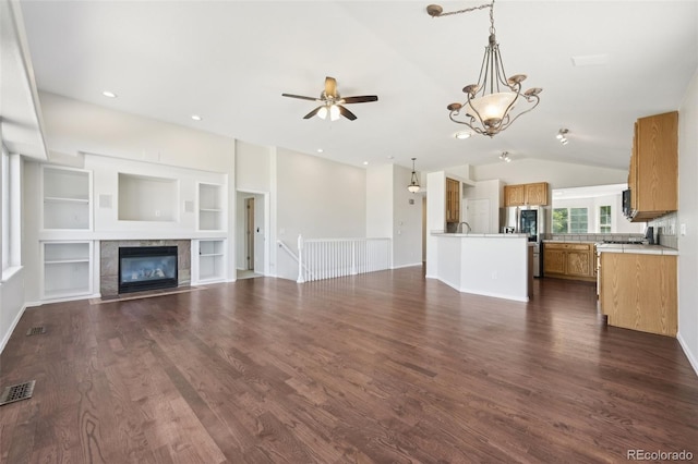 unfurnished living room with dark hardwood / wood-style floors, a fireplace, ceiling fan with notable chandelier, and vaulted ceiling