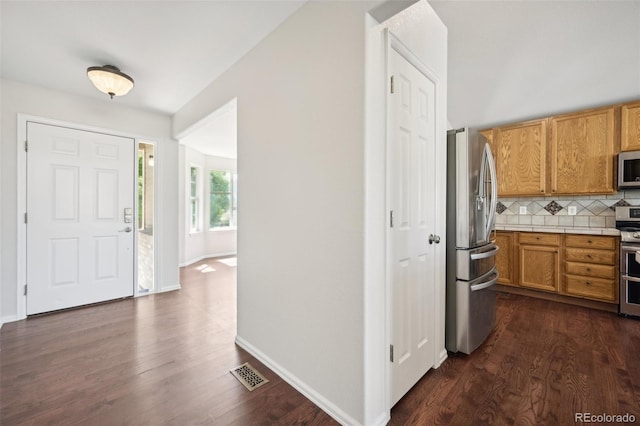 kitchen with dark hardwood / wood-style floors, decorative backsplash, and stainless steel appliances