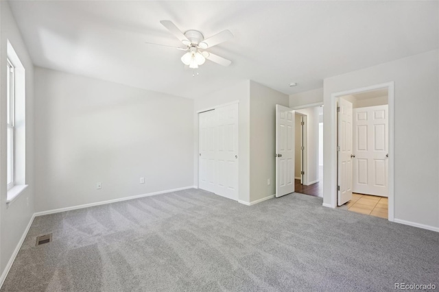 unfurnished bedroom with ceiling fan, a closet, and light colored carpet