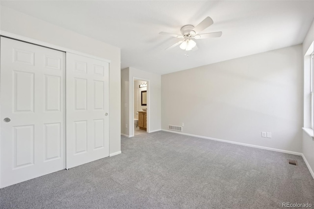 unfurnished bedroom featuring carpet flooring, ceiling fan, connected bathroom, and a closet