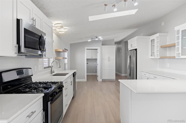 kitchen featuring white cabinetry, stainless steel appliances, vaulted ceiling, and sink