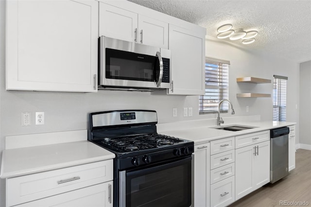 kitchen featuring appliances with stainless steel finishes, sink, a textured ceiling, and white cabinets