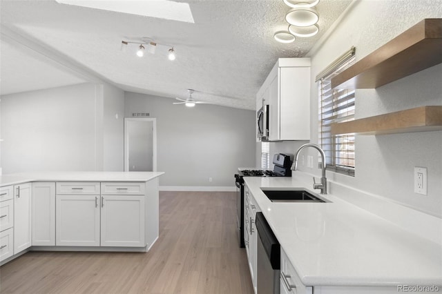 kitchen with white cabinetry, appliances with stainless steel finishes, sink, and lofted ceiling with skylight